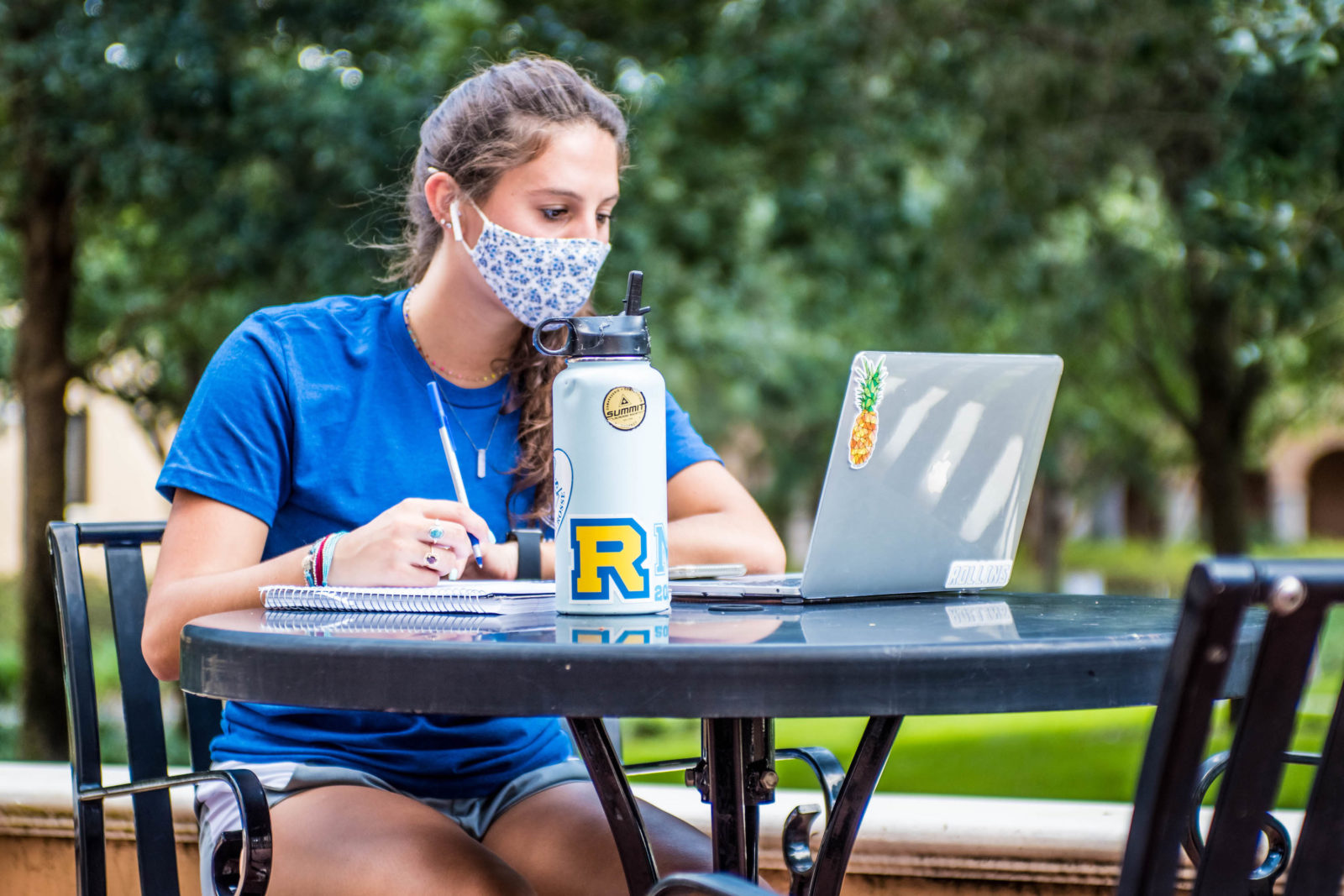 Rollins College student studies outside while wearing a face mask.