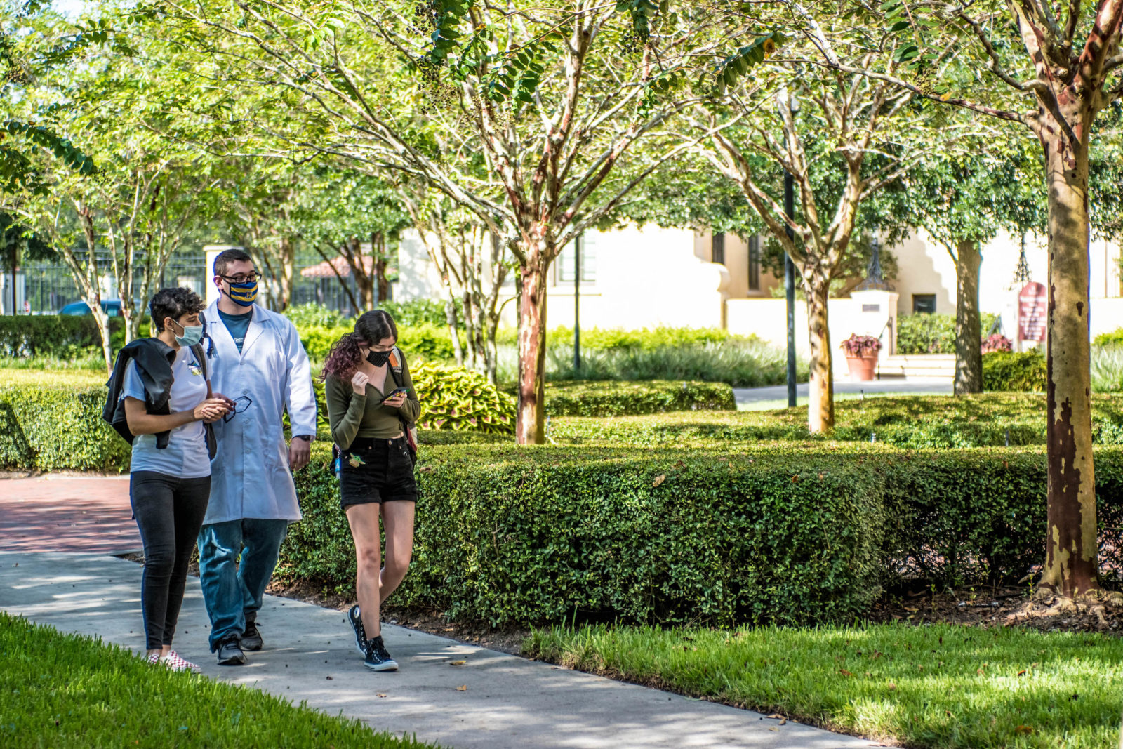 Students at Rollins College walk outdoors with face masks on.