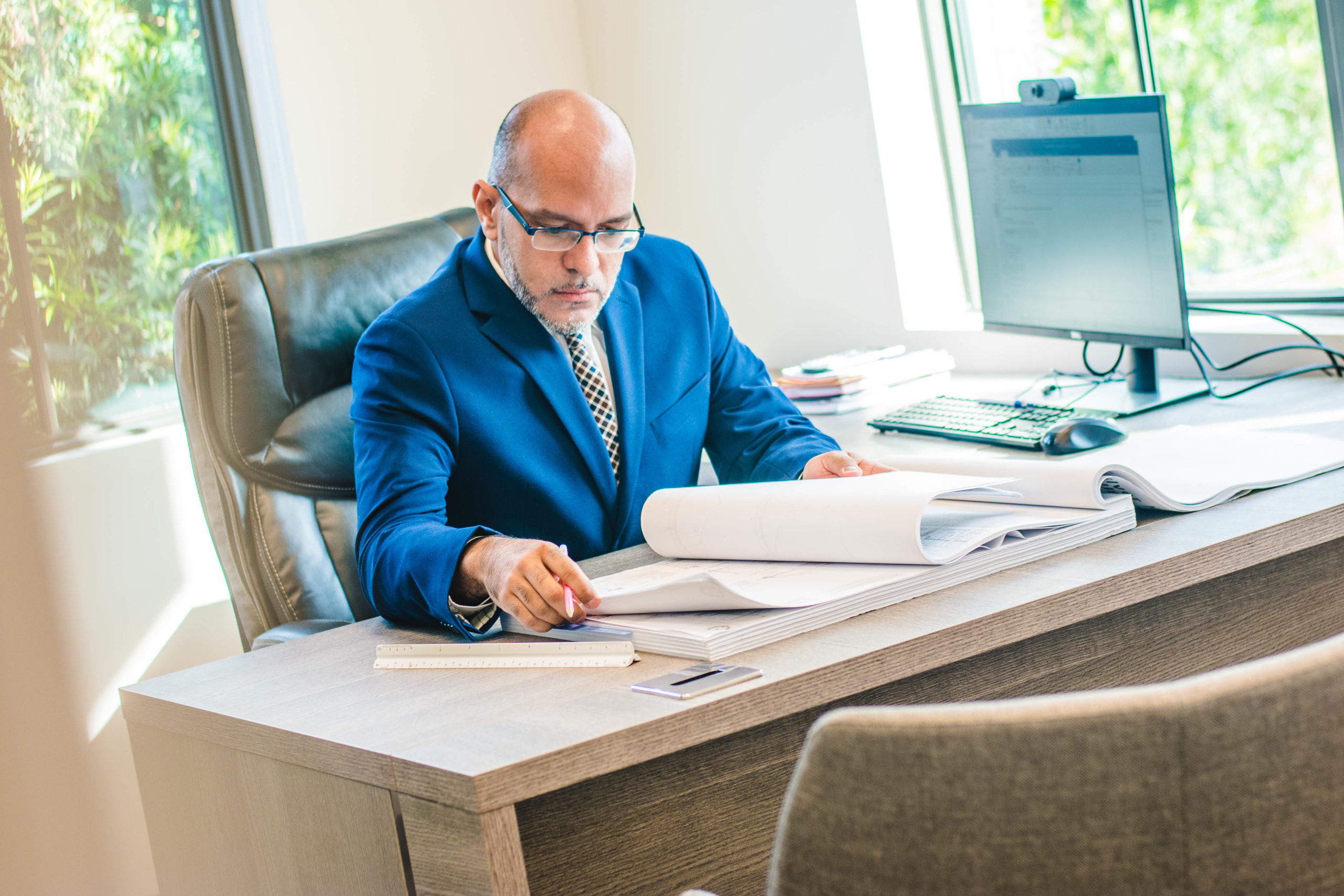 Manuel Velazquez sitting at his desk reviewing blueprints.