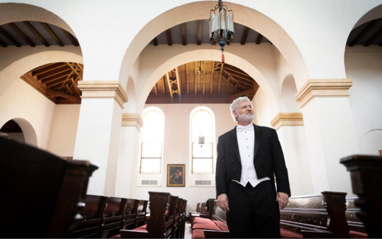 Dr. John V. Sinclair stands in between the pews of Knowles Chapel.