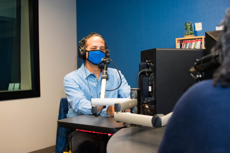 Sam Stark conducts podcast in recording studio.