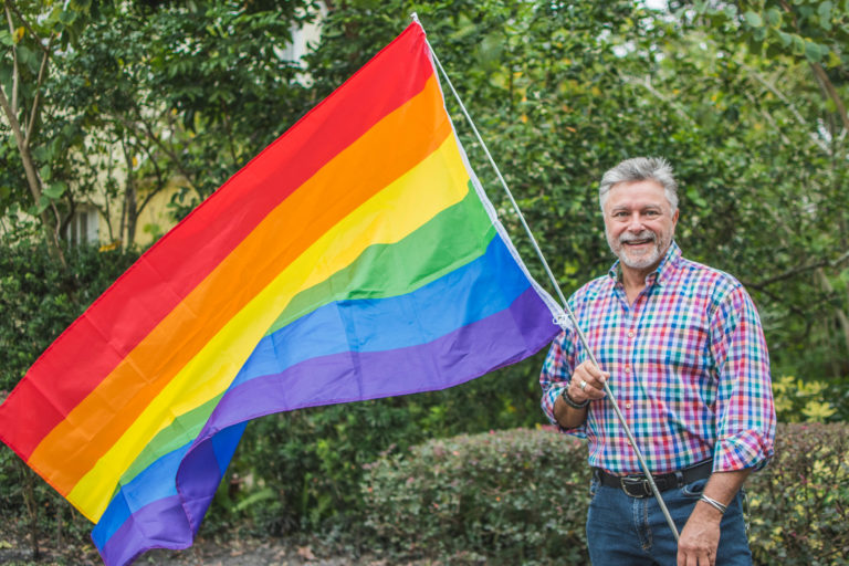 Thor Falk holds up a rainbow LGBTQ pride flag.
