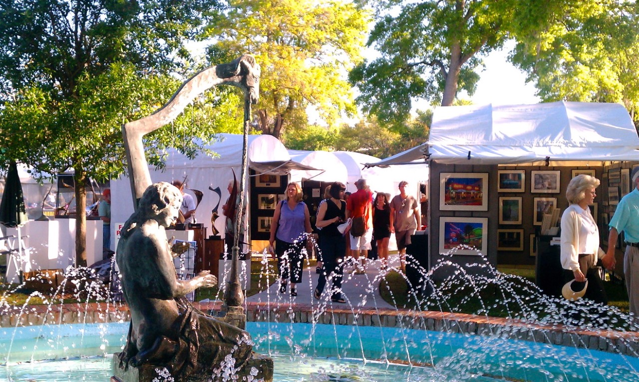 The Sidewalk Art Festival last year shows patrons shopping near a fountain and statue.