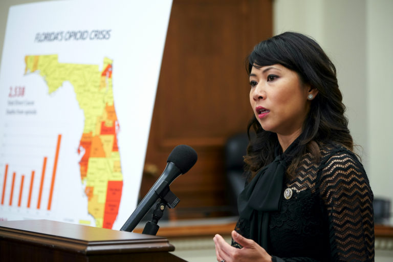 Rep. Stephanie Murphy delivers a speech with a poster of the state of Florida in the background.