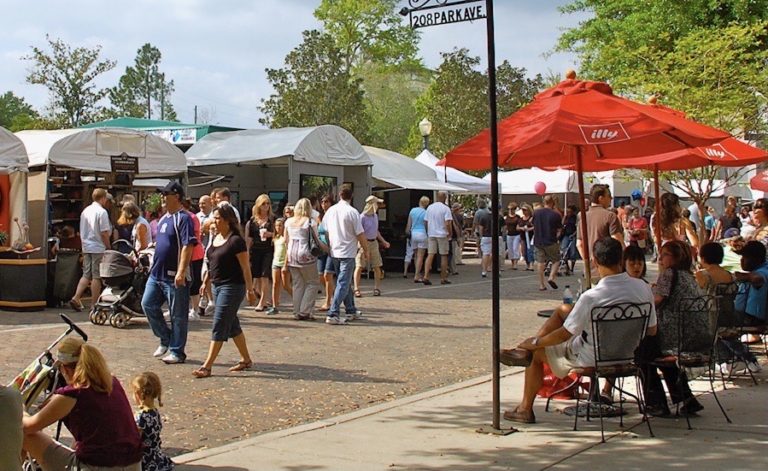 People walking down the street which is lined with tents and the Park Avenue sign.