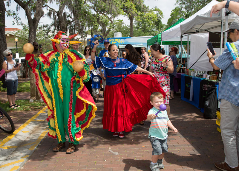 Performers in colorful, traditional clothing dance with patrons at the art festival.