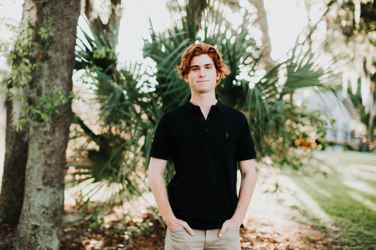 Photo of Harry Carter, a young man with red hair standing in front of trees with a black shirt on.