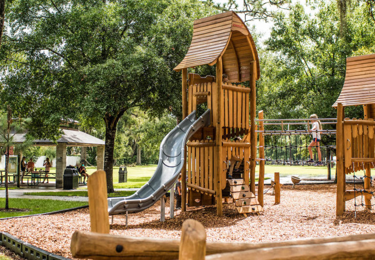 Image shows brown playground green trees