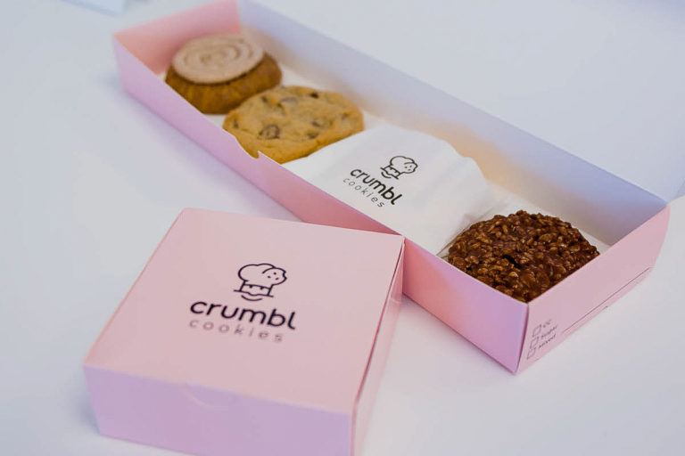 Pink box with four brown, beige, and chocolate cookies