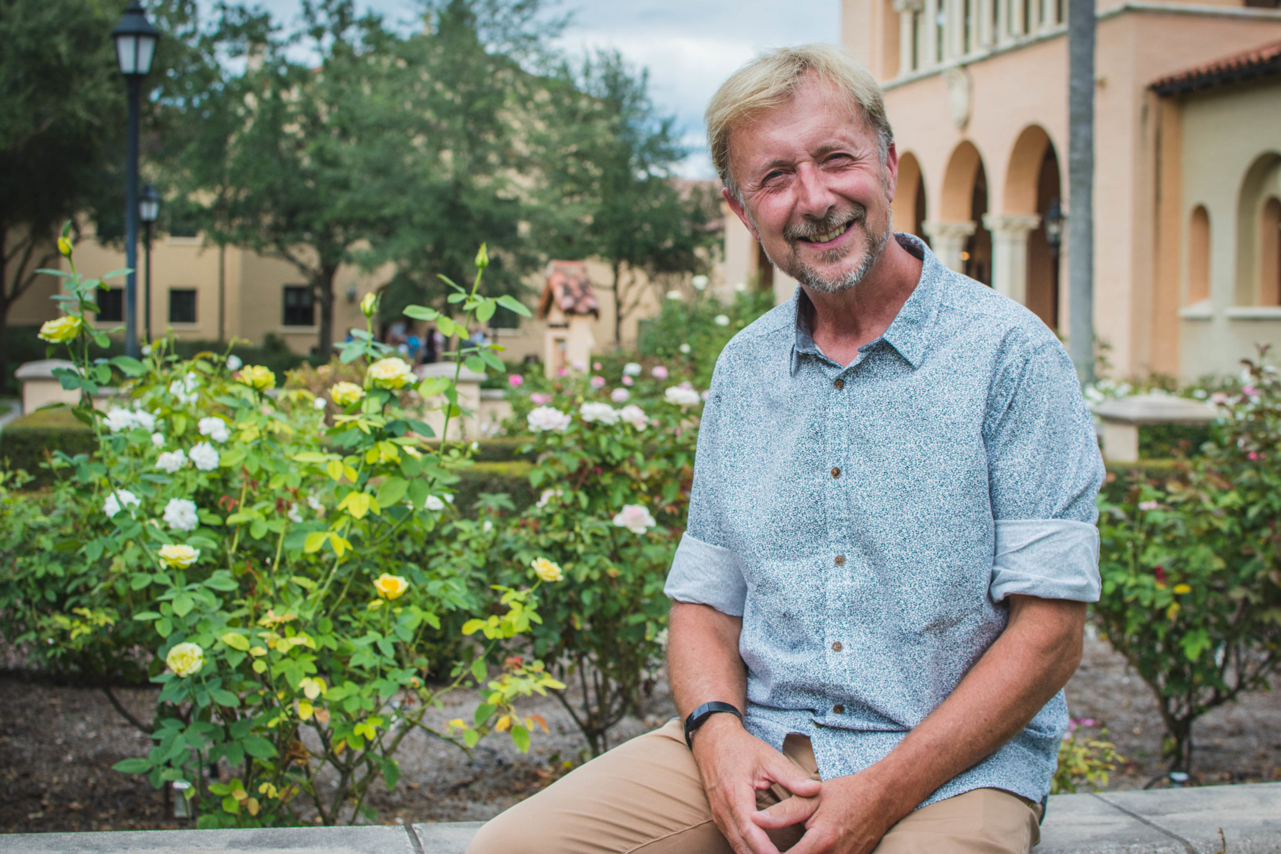 Artist Paul Day sits in front of the Rollins College rose garden.